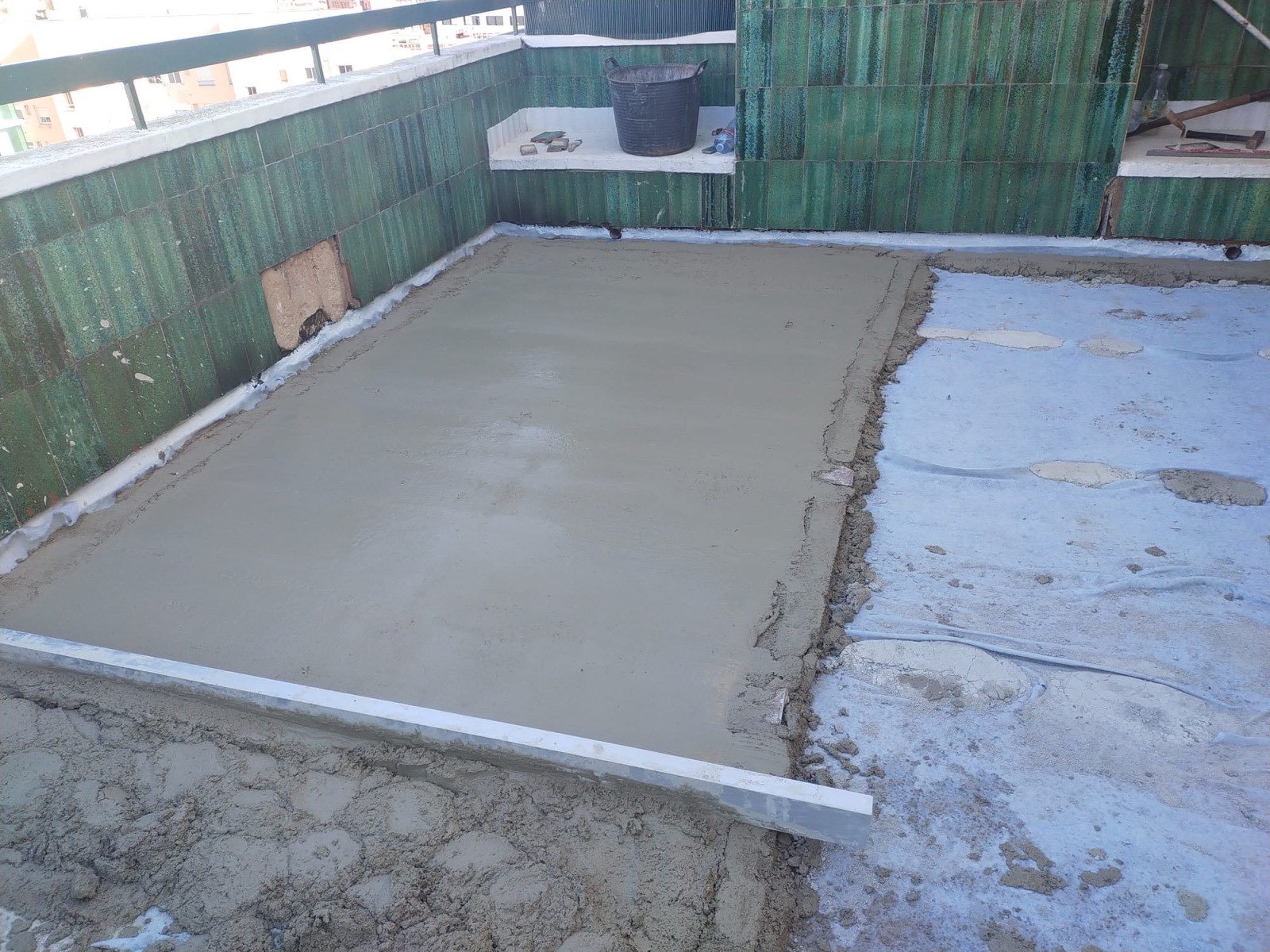Reforma de terraza con solera de mortero recién fresada sobre azulejo verde existente