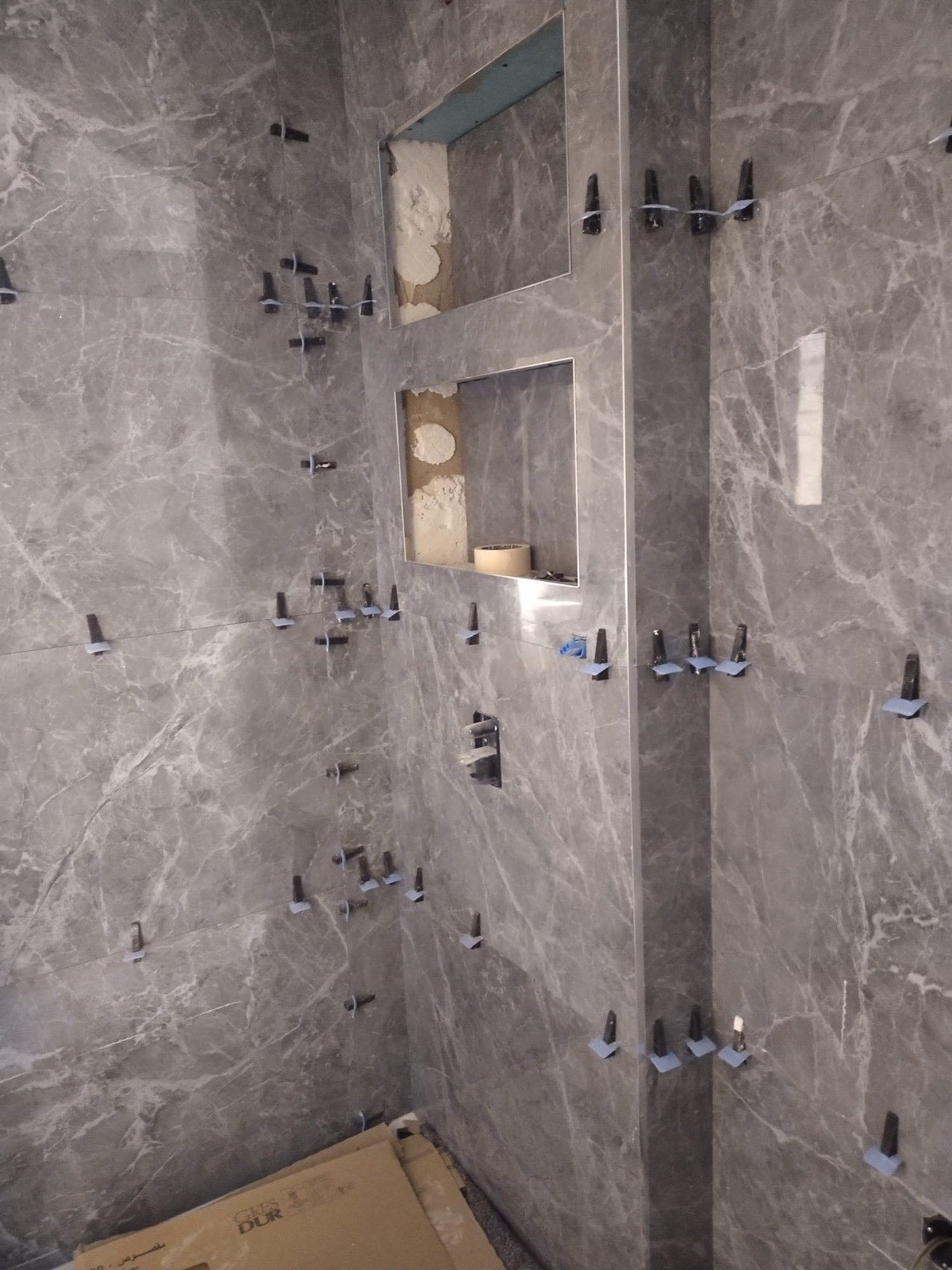 Reforma de baño con alicatado imitación mármol gris y hornacinas empotradas en obra