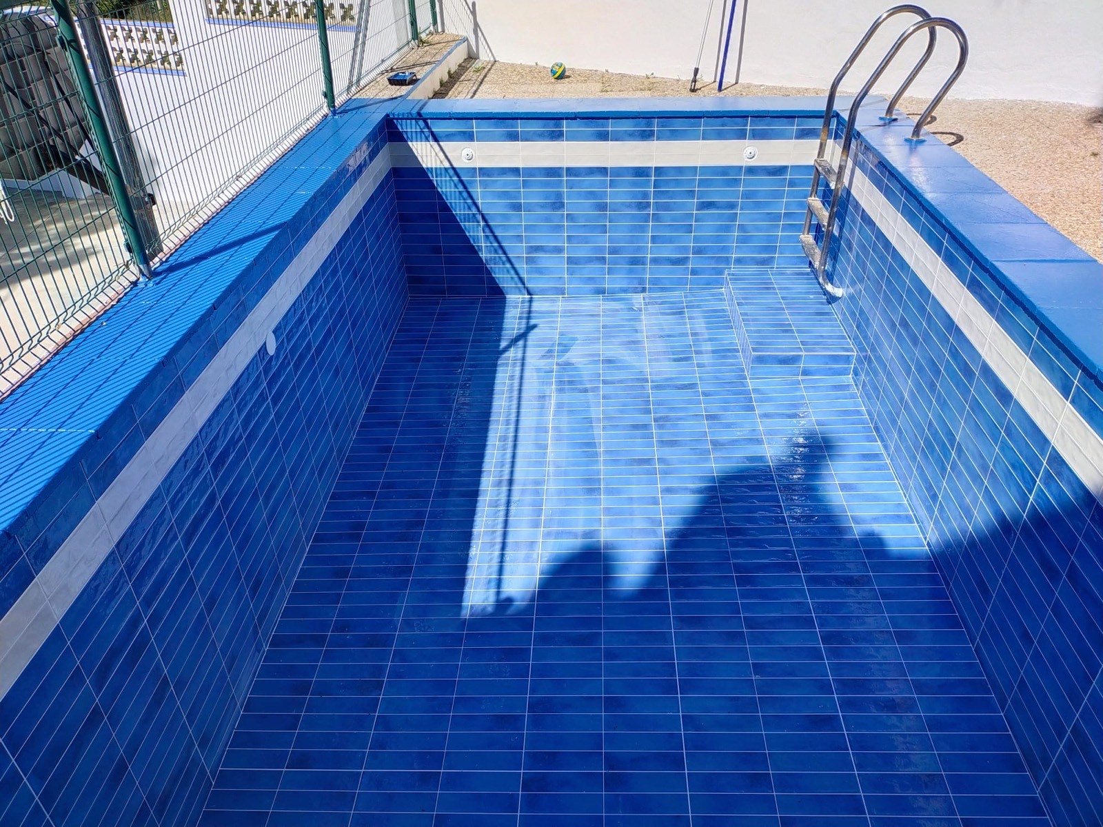 Piscina reformada con alicatado de gres azul y escalera de acero inoxidable