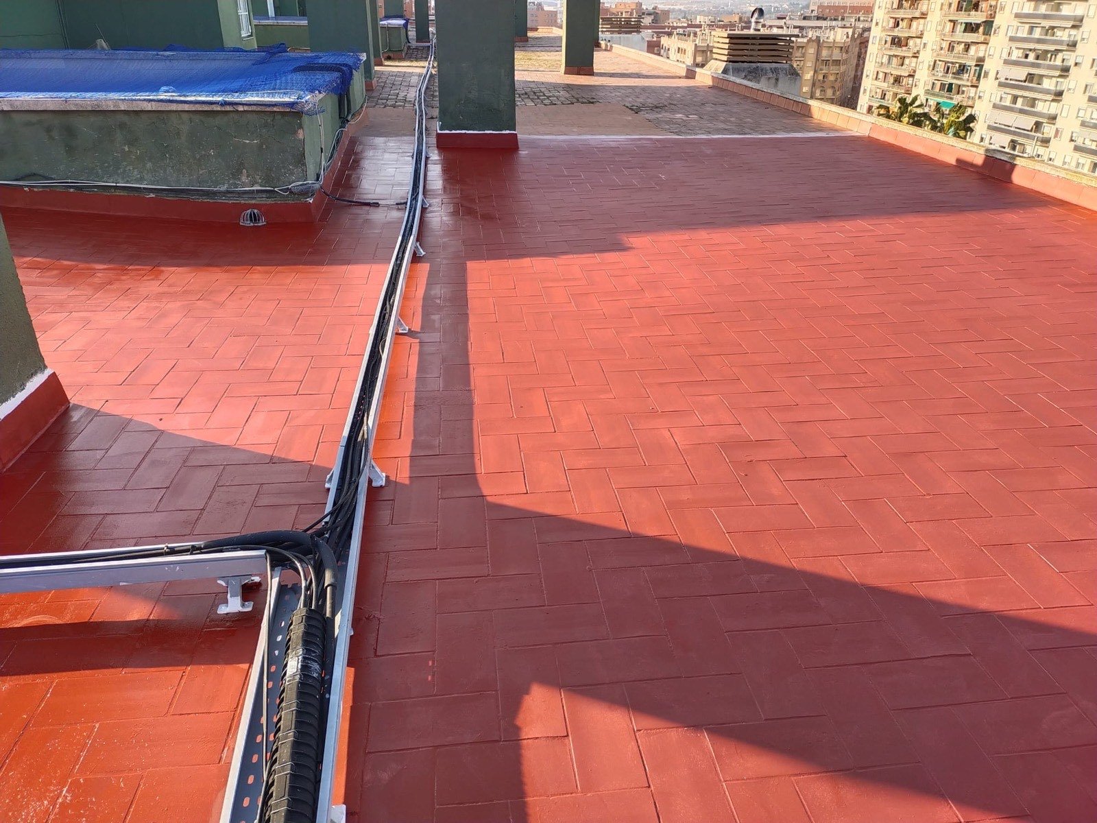 Terraza de azotea reformada con pavimento cerámico rojo y canalización de cables