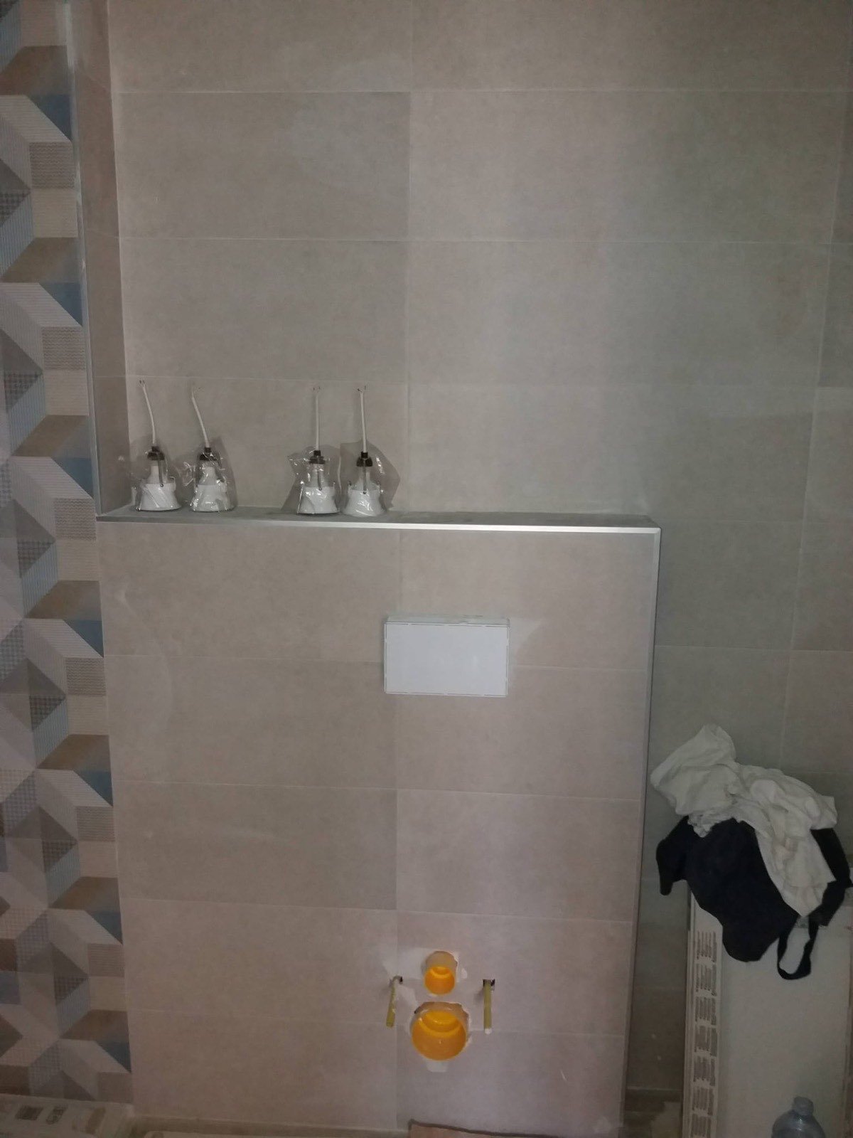 Baño reformado con cisterna empotrada, repisa de obra y alicatado decorativo geométrico