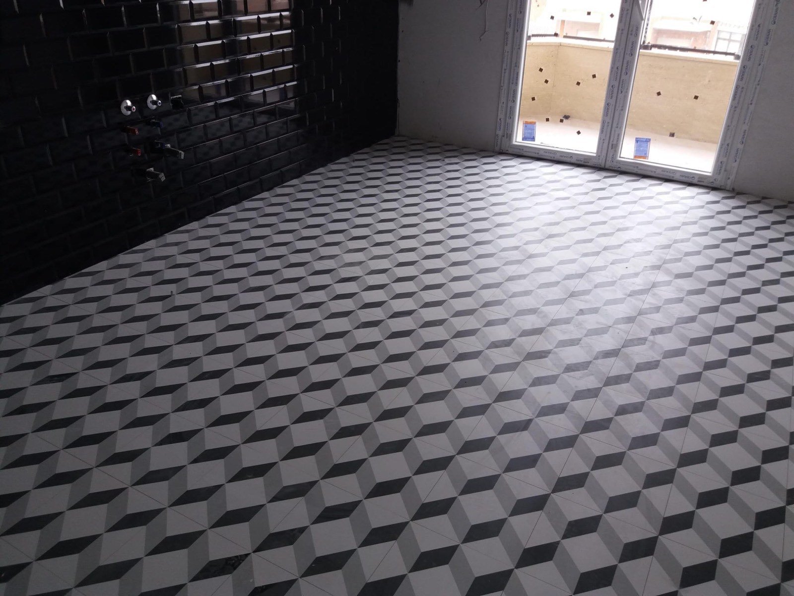 Suelo nuevo con baldosa hidráulica geométrica y pared de azulejo negro en reforma