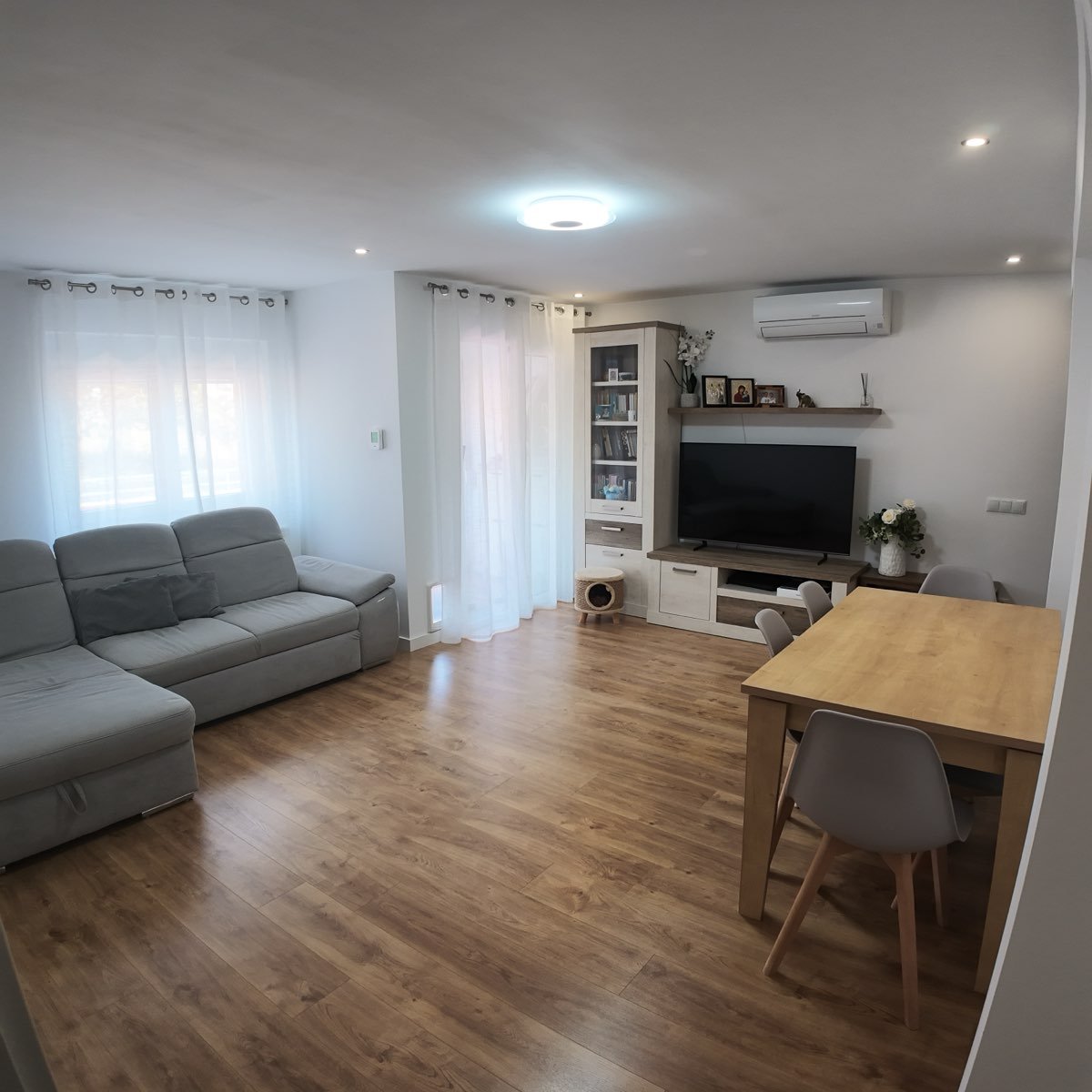 Salón-comedor reformado en Tarragona con suelo efecto madera, mueble de salón y zona de comedor integrada